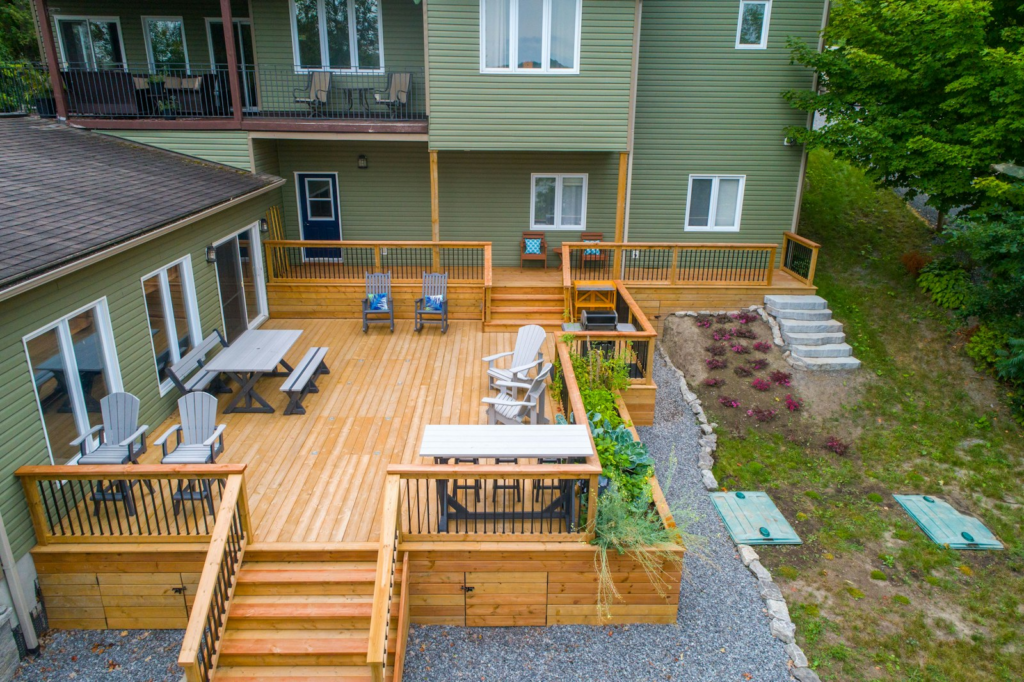 Large natural wood backyard deck with stairs, railings and outdoor seating